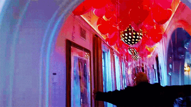 a hallway filled with red balloons and a disco ball
