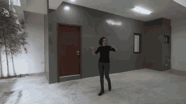 a woman in a black shirt is standing in a room with a door