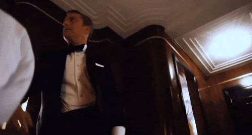 a man in a tuxedo is standing in a dark hallway