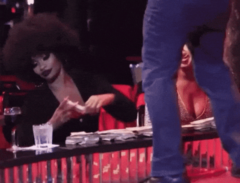 a woman with an afro is sitting at a table with a man standing next to her
