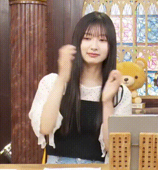 a woman with long hair is sitting at a table with a teddy bear in front of her .