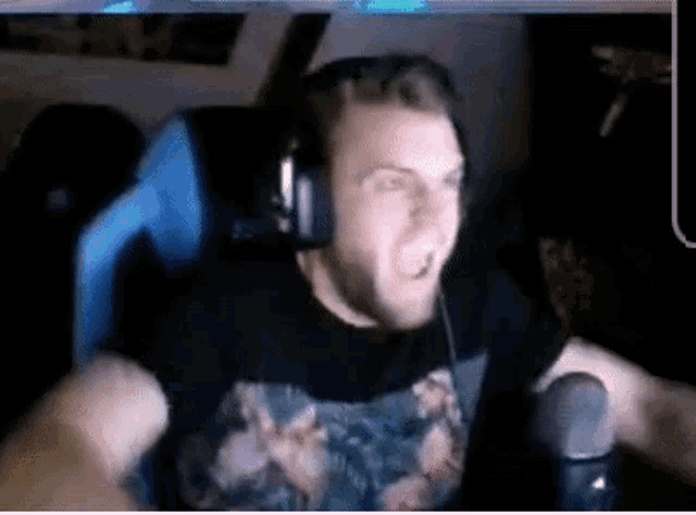 a man wearing headphones and a floral shirt is sitting in a chair in front of a microphone .