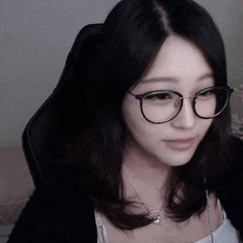 a woman wearing glasses and a necklace with the letter m