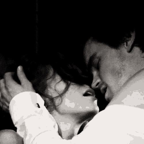 a black and white photo of a man and woman kissing each other .
