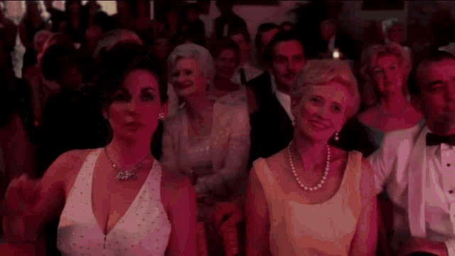 a group of people are sitting in a dark room with pink lights