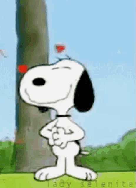 snoopy is standing in front of a tree with his arms crossed .