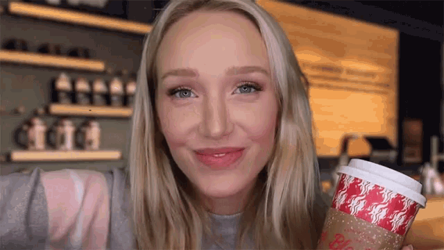 a blonde woman is holding a cup that says ' be happy ' on it