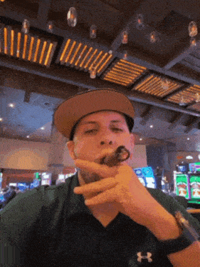 a man wearing an under armour shirt is smoking a cigar in a casino