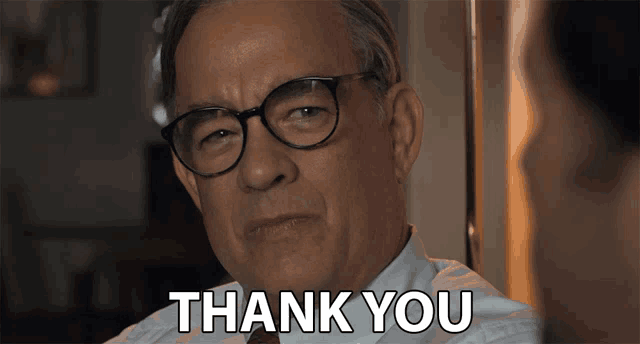 a man wearing glasses says " thank you " in front of him
