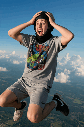 a man wearing a shirt that says iron man is jumping through the air