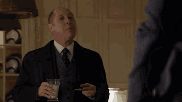 a man in a suit and tie is drinking milk and holding a cookie