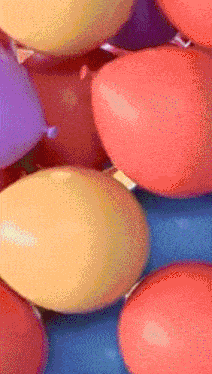 a bunch of different colored balloons stacked on top of each other