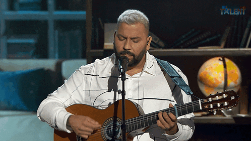 a man singing into a microphone while playing a guitar in front of a sign that says talent