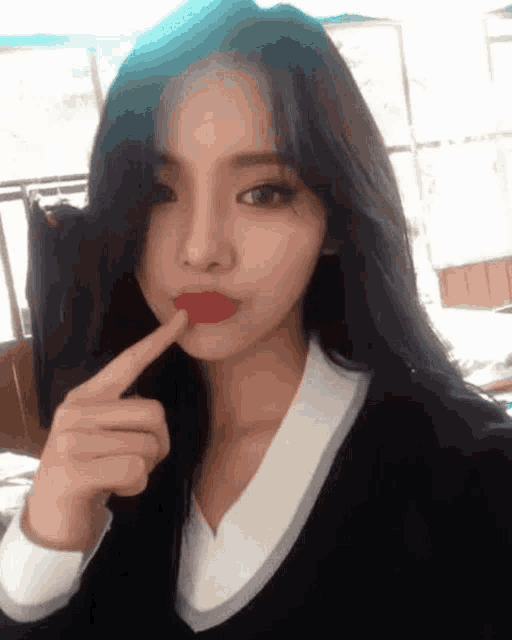 a girl with long black hair and red lips is taking a selfie with her finger in her mouth
