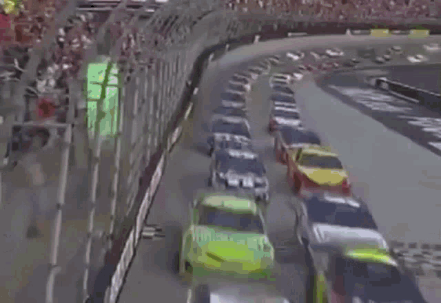 a row of race cars are driving down a track .