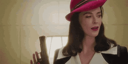 a woman in a pink hat is holding a gun in her hand .