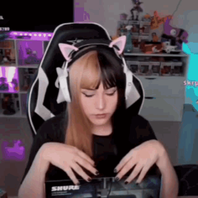 a girl wearing headphones with cat ears is sitting in a gaming chair .