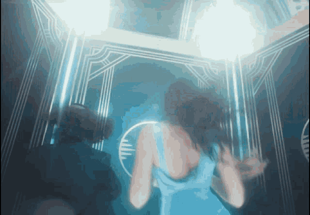 a woman in a blue dress stands in front of a mirror