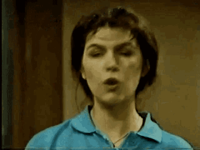a woman in a blue shirt is blowing a kiss .