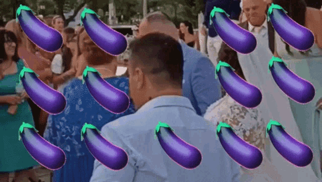 a man in a blue shirt stands in front of a bunch of purple eggplant emojis