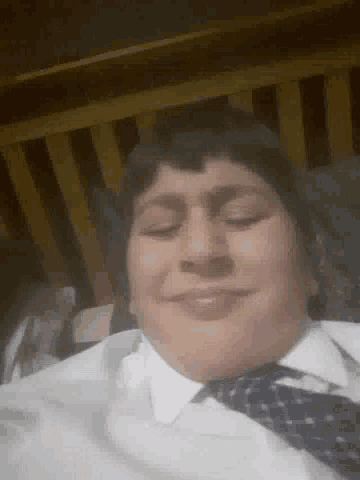 a man wearing a white shirt and tie is laying down with his eyes closed