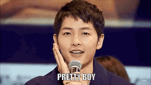 a young man is holding a microphone and says pretty boy .