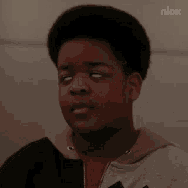 a young man with his eyes closed is wearing a hoodie and a red shirt .