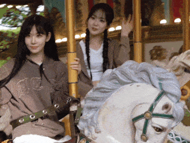 two girls are riding a merry go round with one wearing a hoodie that says aoc