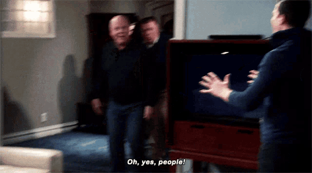 a man standing in front of a television says " oh yes people "