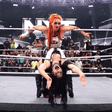 a wrestler holds another wrestler upside down in a ring