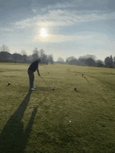 a man swings a golf club at a golf ball on a golf course