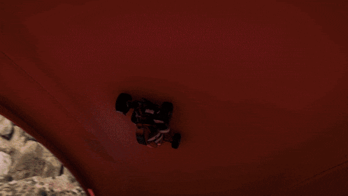 a car is going down a red track with a cliff in the background