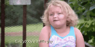 a little girl is sitting on a bench with the words `` everybody 's a little gay '' .