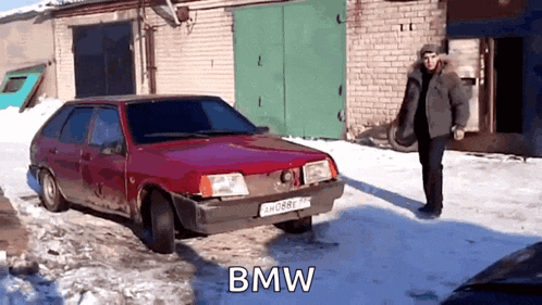 a man is standing next to a red bmw car