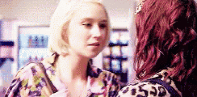 two women are talking to each other in a store . one of the women is blonde and the other is red .