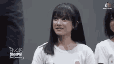 a girl in a white shirt is looking at the camera .
