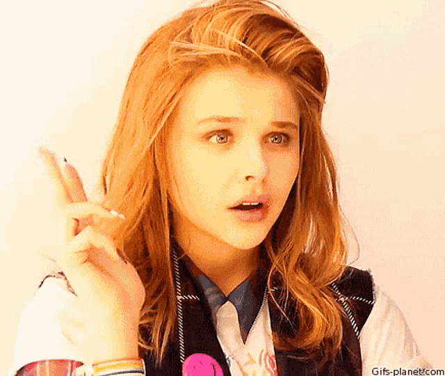 a woman with red hair is making a peace sign with her hand