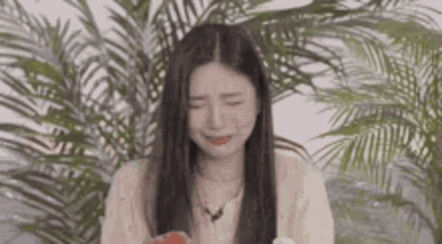 a woman is crying while eating a slice of watermelon .