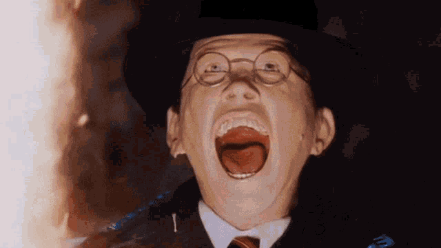 a man wearing glasses and a hat is screaming with his mouth open