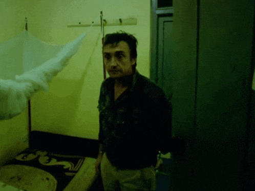 a man is standing in a dark room with a mosquito net hanging on the wall
