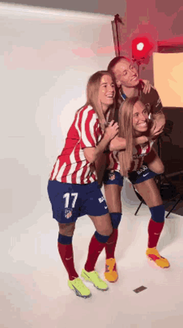 three female soccer players posing for a picture with one wearing number 17