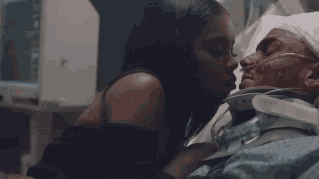a woman is kissing a man in a hospital bed with a broken neck