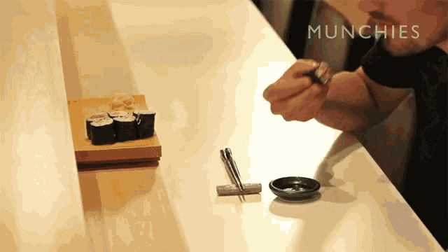 a man is eating sushi at a counter that says munchies on it