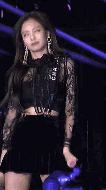 a woman wearing a black crop top and a black skirt with a chanel strap around her waist