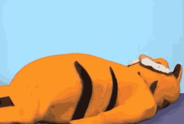 garfield the cat is laying down on a purple surface .