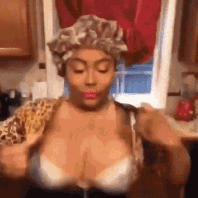 a woman wearing a shower cap is taking off her bra in front of a window