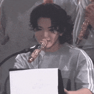 a young man is singing into a microphone while sitting at a table .