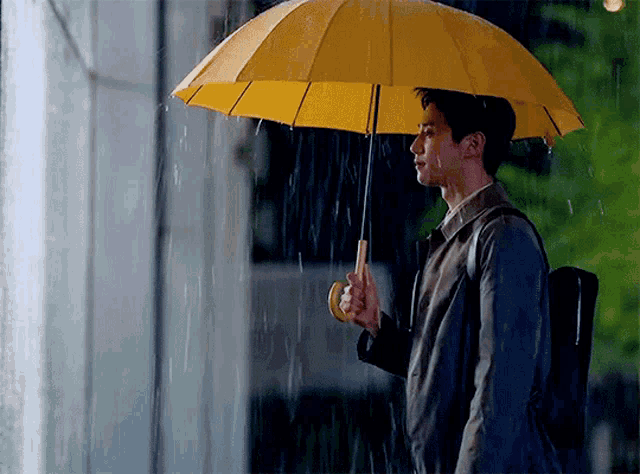 a man with a yellow umbrella in the rain