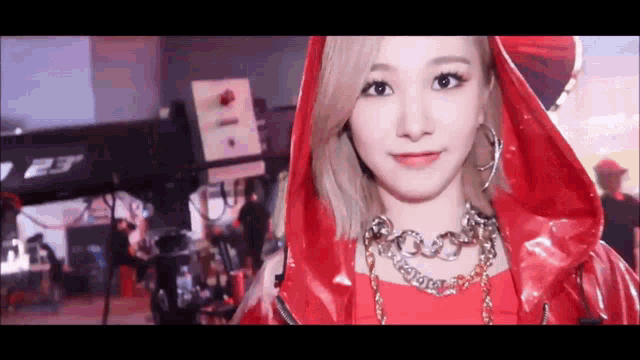a close up of a woman wearing a red hooded jacket and earrings .