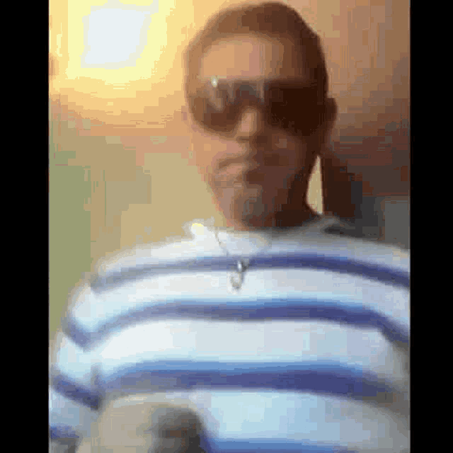 a man wearing sunglasses and a striped shirt is looking at the camera